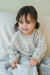 Toddler girl smiling in Avauma Maple Oat pajama set – cozy floral sleepwear for baby girls